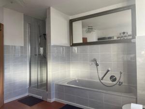 y baño con bañera y ducha con espejo. en Dachwohnung mit Sonnenterrasse, en Flörsheim 23 fotos más