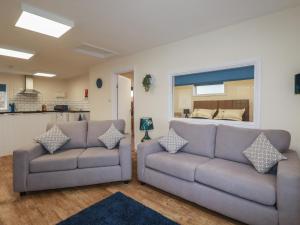 a living room with two couches and a kitchen at Kingfisher Lodge in St Austell