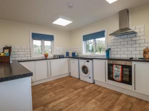 a kitchen with white cabinets and a washer and dryer at Kingfisher Lodge in St Austell +14 photos