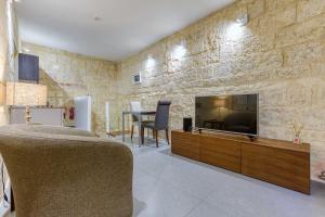 a living room with a tv on a stone wall at Cosy 1BR home in the heart of vibrant Valletta by 360 Estates in Valletta