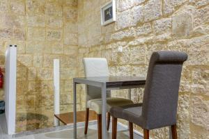 a table and chairs in a room with a stone wall at Cosy 1BR home in the heart of vibrant Valletta by 360 Estates in Valletta