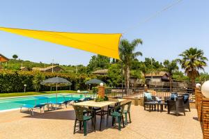 a patio with a table and chairs and a pool at Villa Aura in Piedimonte Etneo