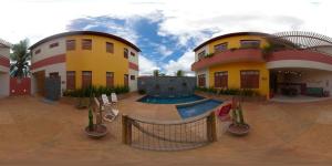 two buildings with a swimming pool in a courtyard at Cardeiro Flat in São Miguel do Gostoso