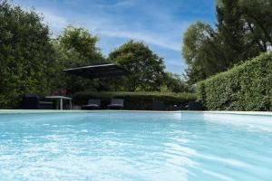 a swimming pool with an umbrella and chairs at B&B LA FESSARDIERE Piscine - Jacuzzi in Saint-Maurice-sur-Fessard