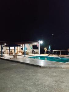 una piscina notturna con tavolo e pianoforte di Chácara Sonho Verde a Bueno Brandão
