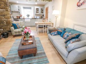 een woonkamer met een bank en een tafel bij River Dance Cottage in Leyburn