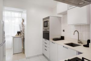 a white kitchen with a sink and a microwave at Luz & Mar at Coastal Oeiras in Oeiras