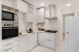 a white kitchen with white cabinets and a refrigerator at Luz & Mar at Coastal Oeiras in Oeiras