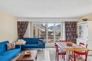 a living room with a blue couch and a table at Triplex in Villars Centre with Parking - Totally Renovated in Villars-sur-Ollon