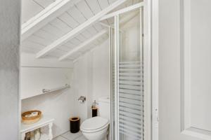 a white bathroom with a toilet and a window at Triplex in Villars Centre with Parking - Totally Renovated in Villars-sur-Ollon