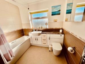 a bathroom with a sink and a toilet and a tub at Ireby House Spacious farm cottage in Morpeth +14 photos
