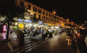 a city street at night with people sitting at tables at Elegante e Comodo - A pochi minuti dall'Aeroporto in Fiumicino