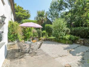 a patio with a table with an umbrella and chairs at 2 Rose Cottage in St. Agnes 