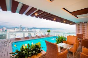 een zwembad op het dak van een gebouw met stoelen bij Balcony Nha Trang Hotel in Nha Trang
