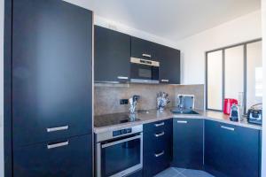 a kitchen with blue cabinets and a sink and a microwave at Atelier Edonya - Au coeur de la Teste in La Teste-de-Buch +5 photos