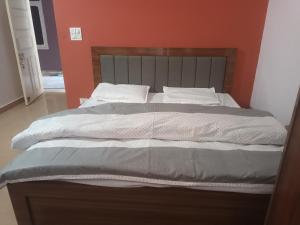 a large bed in a bedroom with an orange wall at Hotel Royal Place in Rāmpur