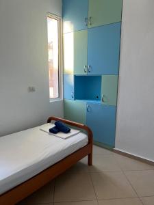 a bedroom with a bed with blue cabinets and a window at Saranda Spot Apartment in Sarandë