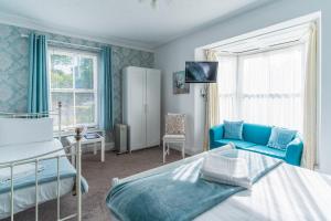a bedroom with a bed and a blue chair at Rooms at The Highcliffe in Aberporth