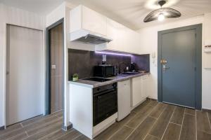 La cuisine est équipée de placards blancs et d'un four avec plaques de cuisson noires. dans l'établissement Panoramique balcon wifi centre-ville, à Millau