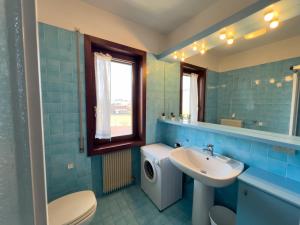 a blue bathroom with a sink and a washing machine at 10 minuti a piedi dal centro - Zona Tranquilla e Silenziosa in Asiago +12 photos