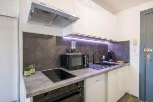 une cuisine avec un évier et un micro-ondes dans l'établissement Panoramique balcon wifi centre-ville, à Millau