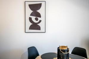 een tafel met stoelen en een foto aan de muur bij Panoramique balcon wifi centre-ville in Millau +12 foto's