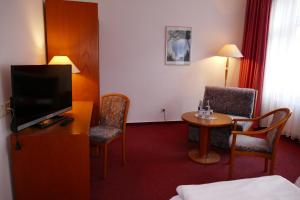 ein Hotelzimmer mit einem TV, einem Tisch und Stühlen in der Unterkunft Hotel Am Dom in Greifswald
