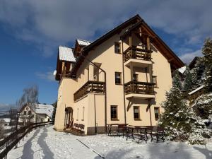 een gebouw met tafels en stoelen in de sneeuw bij Dom Madeyski in Szczawnica