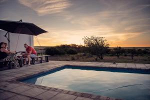 a man and woman sitting on a bench next to a pool at Donsveertjie Gasteplaas & Venue in Heilbron