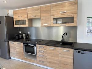 a kitchen with wooden cabinets and a stainless steel refrigerator at Appartement avec jacuzzi in Porto-Vecchio