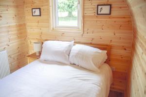 een slaapkamer met een wit bed in een houten muur bij Winter Recharge - Secluded Luxury Cabins with stream, stargazing, bookable sauna, walks and nature - Fell Farm Hideaway in Colwell