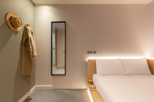 a bedroom with a bed and a mirror on the wall at Zedwell Hotel Greenwich in London