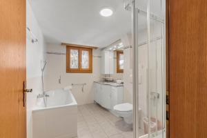 a bathroom with a tub and a toilet and a sink at Appartement chaleureux près de Saas-Fee in Saas-Grund +12 photos