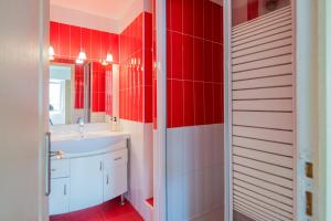 La salle de bains est pourvue de murs rouges et d'un lavabo blanc. dans l'établissement La Bellevue en plein du coeur centre-ville avec wifi, à Millau