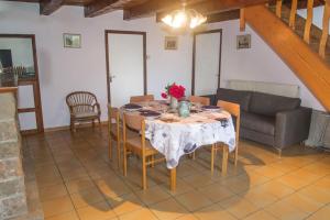 a dining room with a table and a couch at Gite l'anemone in Saint-Pierre-des-Tripiers +4 photos