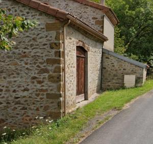 a brick building with a door on the side of a road at Maison de campagne 60m2 in Tailhac