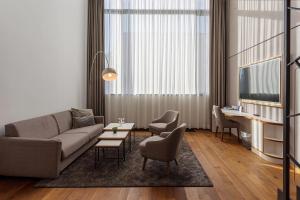 een woonkamer met een bank, stoelen en een tv bij Mercure Hotel MOA Berlin in Berlijn