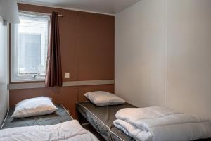 dwa łóżka ustawione w pokoju z oknem w obiekcie Mobil-home 2 chambres - B w mieście Saint-Jean-de-Monts