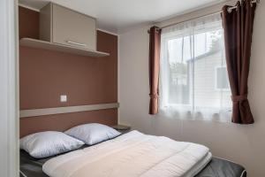 łóżko z 2 poduszkami w pokoju z oknem w obiekcie Mobil-home 2 chambres - B w mieście Saint-Jean-de-Monts