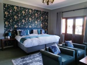 察嫩Magoebaskloof Hotel的一间卧室，里面有一张床和两把蓝色椅子
