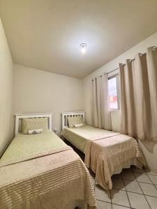 two beds in a room with a window at 03 Apartamento Asa Branca in Caruaru