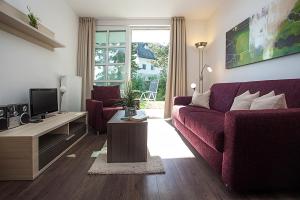 a living room with a purple couch and a tv at Residenz am Balmer See - BS 03 mit Wellnessbereich in Balm