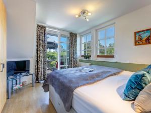 a bedroom with a bed and a tv and windows at Residenz am Balmer See - BS 69 mit Wellnessbereich in Balm +20 photos