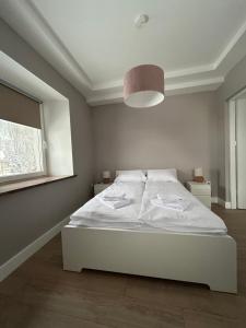a white bed in a room with a window at Apartament Kryształ 2 in Piechowice