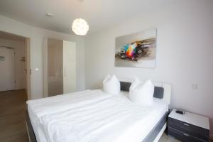 a bedroom with a white bed with a painting on the wall at Residenz am Balmer See - BS 09 mit Wellnessbereich in Balm