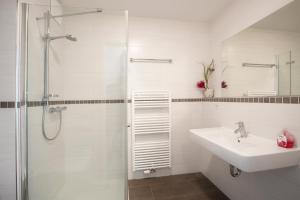 a white bathroom with a sink and a shower at Residenz am Balmer See - BS 09 mit Wellnessbereich in Balm