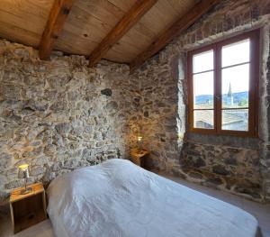 ein Schlafzimmer mit einem Bett in einer Steinmauer in der Unterkunft Maison Le Levant à Chauzon in Chauzon