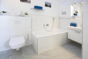 a white bathroom with a toilet and a sink at Residenz am Balmer See - BS 31 mit Wellnessbereich in Balm +19 photos