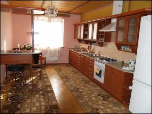 kuchnia z drewnianymi szafkami, stołem i blatem w obiekcie Apartament Sanitarna 17 w Lwowie