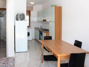 kuchnia z drewnianym stołem i białą lodówką w obiekcie Apartment Casa Debora-1 by Interhome w mieście Rosolina Mare +14 zdjęć